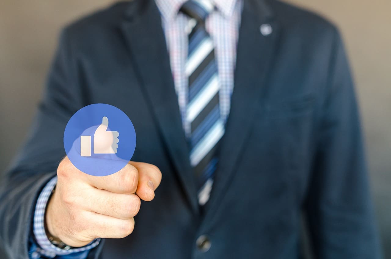 A man in a suit holding up a blue button.