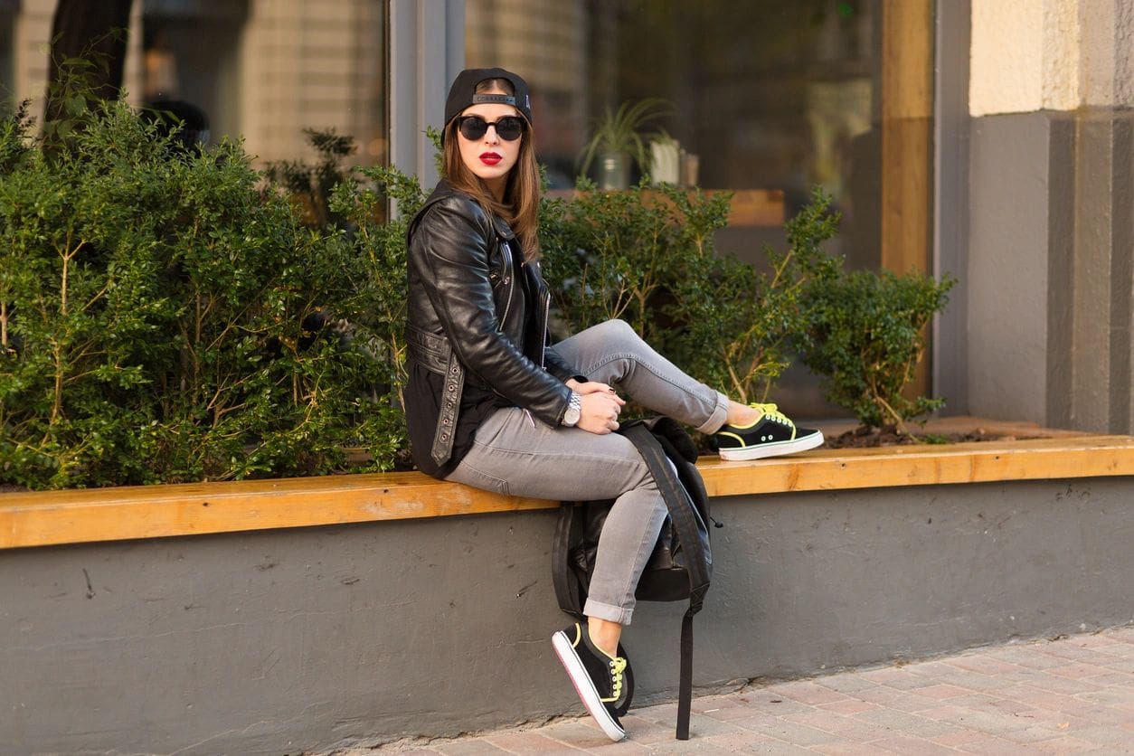 A woman sitting on the side of a building.