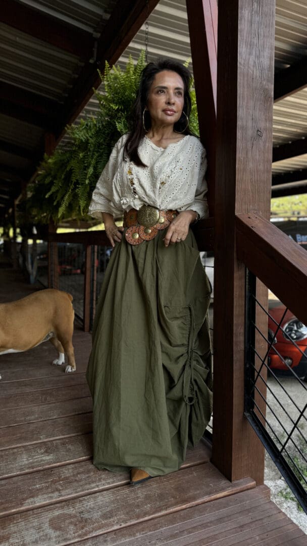 A woman in a long skirt standing next to a dog.